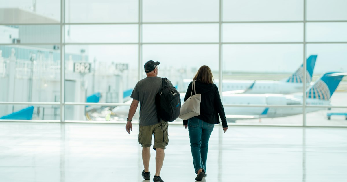 Cuplu cu bagaje mergând prin aeroport, spre casă