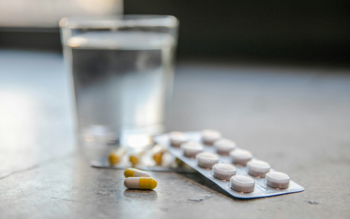 Pahar cu apă și pastile analgezice